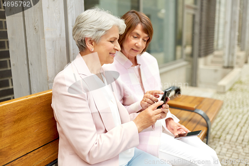 Image of happy senior women with smartphones in city