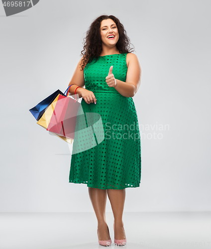 Image of happy woman with shopping bags showing thumbs up