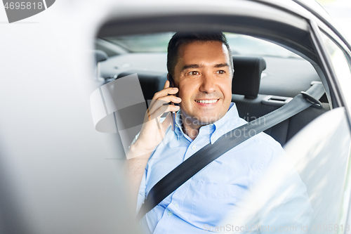 Image of male passenger calling on smartphone in taxi car