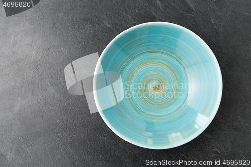 Image of close up of blue ceramic plate on slate background