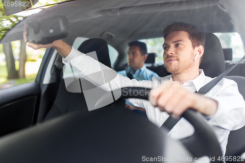 Image of male driver with wireless earphones driving car