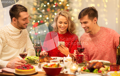 Image of friends with cellphone celebrate christmas at home