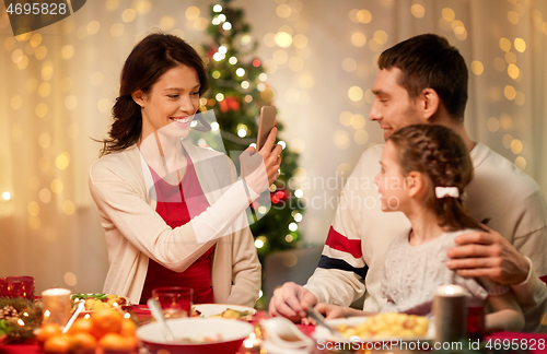 Image of happy family taking picture at christmas dinner