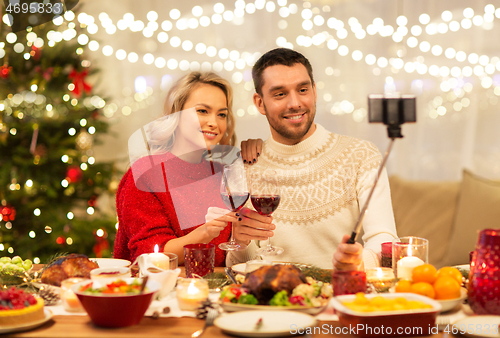 Image of couple taking picture by selfie stick at christmas