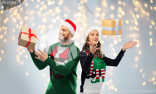 Image of happy couple in ugly sweaters with christmas gift