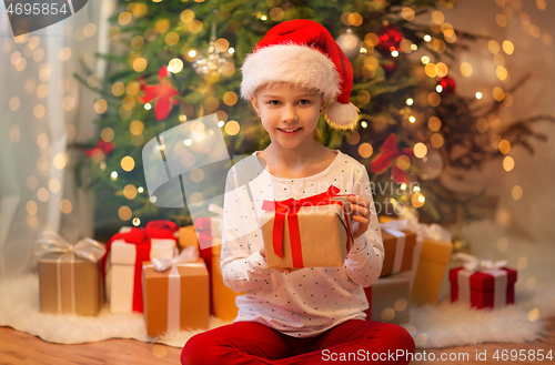 Image of smiling girl in santa hat with christmas gift