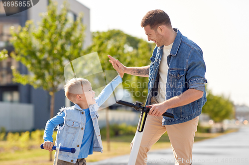 Image of father and son with scooters making high five