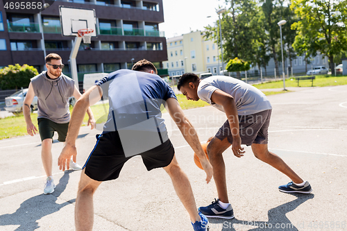 Image of group of male friends playing street basketball