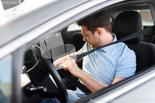 Image of man or car driver fastening seat belt