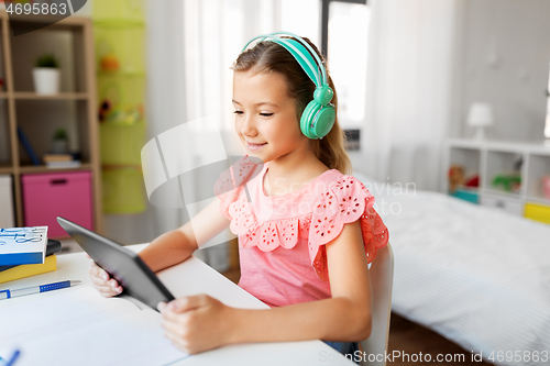 Image of girl in headphones with tablet computer at home