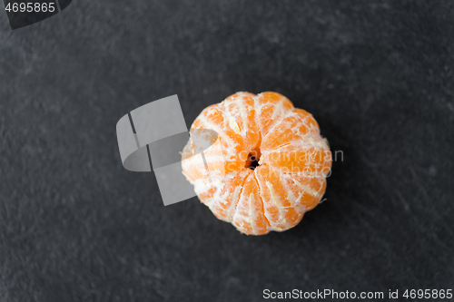 Image of close up of peeled mandarin on slate table top