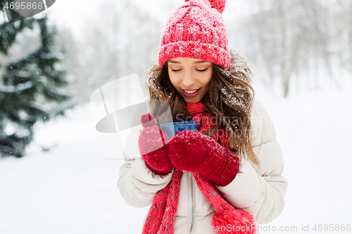 Image of happy young woman with tea cup in winter park