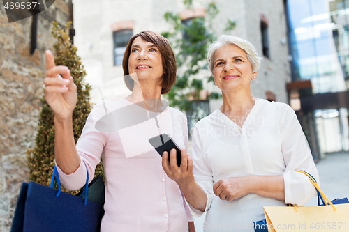 Image of old women with shopping bags and cellphone in city