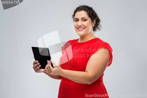 Image of happy woman in red dress using tablet computer