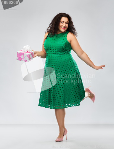 Image of happy woman in green dress holding gift box