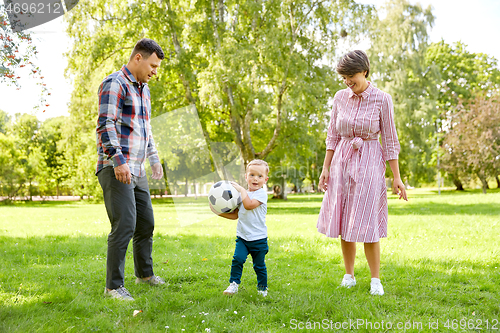 Image of happy family playing soccer at summer park