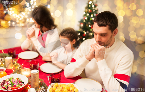 Image of family praying before meal at christmas dinner