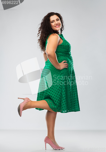 Image of happy woman in green dress over grey background