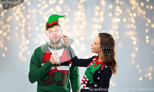 Image of couple with christmas party props in ugly sweaters