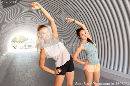 Image of women with fitness trackers stretching outdoors
