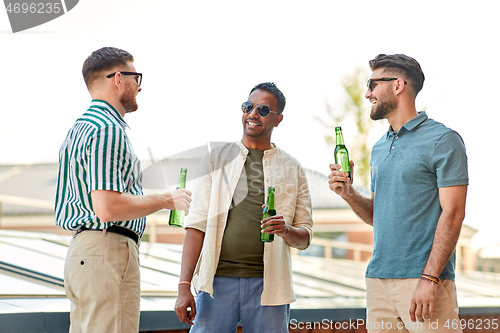 Image of happy male friends drinking beer at rooftop party