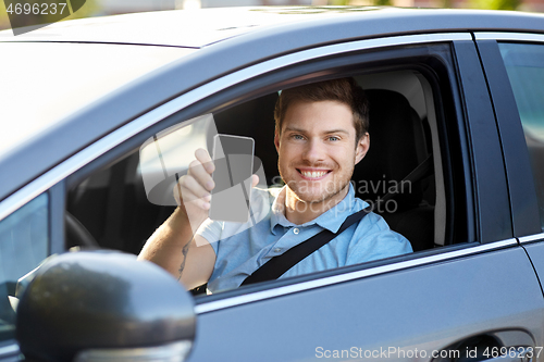 Image of man or car driver showing smartphone