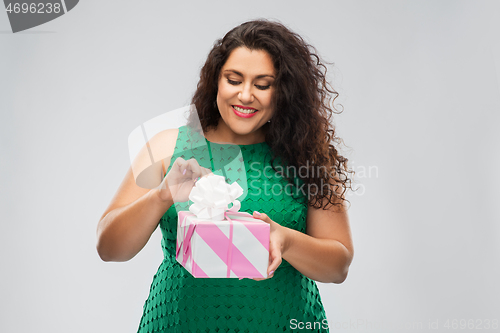 Image of happy woman in green dress opening gift box