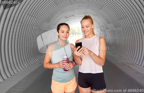 Image of women or female friends with smartphone and flask