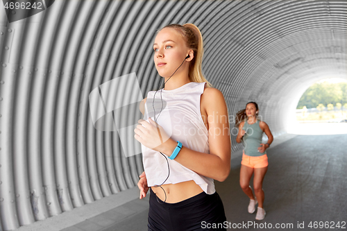 Image of women or female friends with earphones running