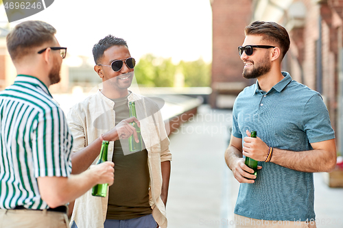 Image of happy male friends drinking beer at rooftop party