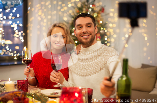 Image of couple taking picture by selfie stick at christmas