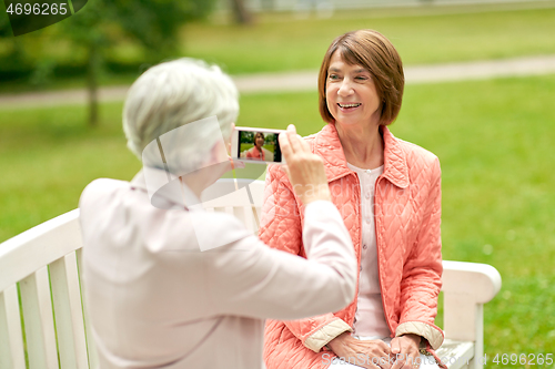 Image of senior woman photographing her friend at park