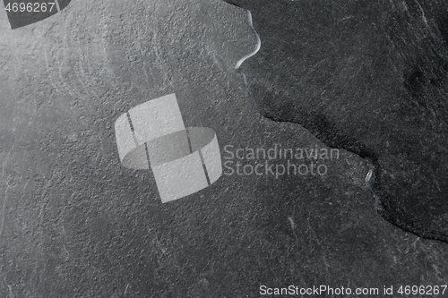 Image of spilled water on black slate stone background