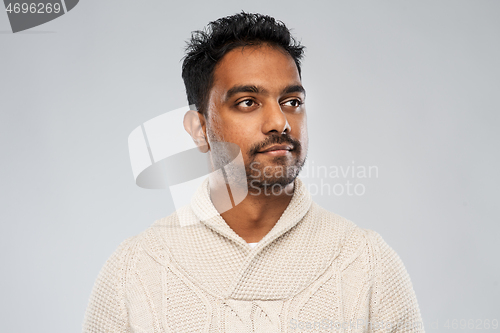 Image of indian man in knitted sweater over gray background