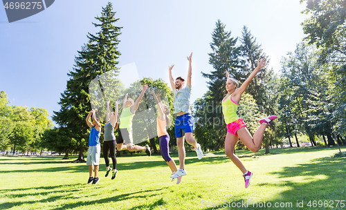 Image of group of happy friends jumping high at park