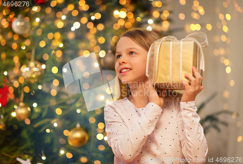 Image of smiling girl with christmas gift at home