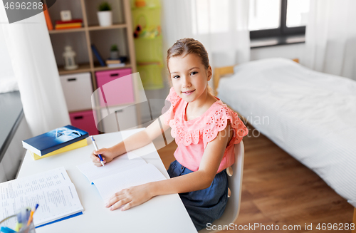 Image of student girl with book writing to notebook at home