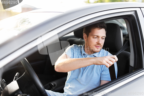 Image of man or car driver fastening seat belt