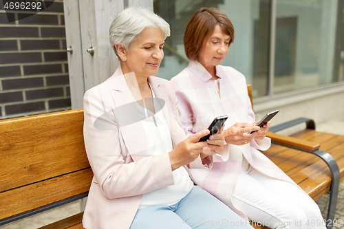 Image of happy senior women with smartphones in city