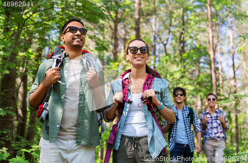 Image of group of friends with backpacks hiking in forest