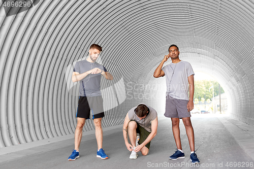 Image of male friends with earphones training outdoors