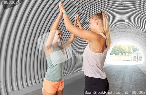 Image of happy women with fitness trackers making high five