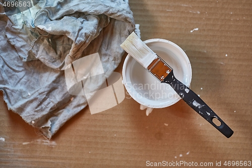 Image of Paint brush on a can of white wall paint