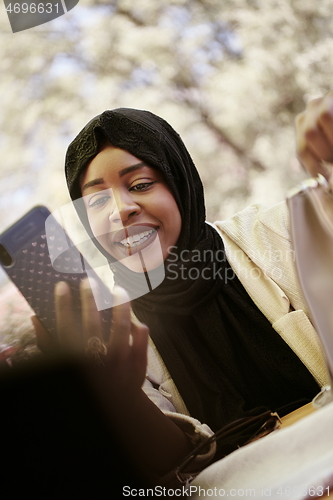 Image of african woman using smartphone wearing traditional islamic clothes