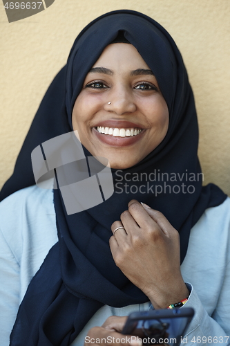 Image of african woman using smartphone wearing traditional islamic clothes