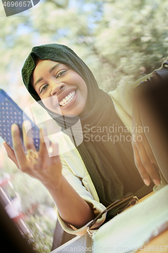 Image of african woman using smartphone wearing traditional islamic clothes