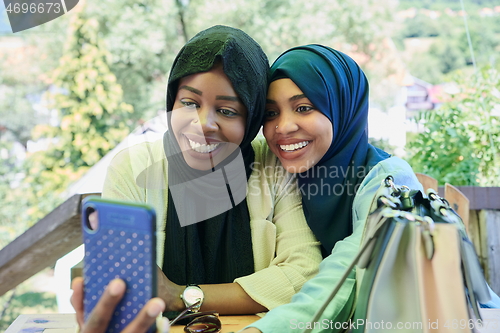 Image of african female friends using smart phone together