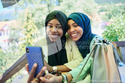 Image of african female friends using smart phone together