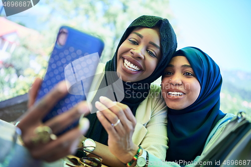 Image of african female friends using smart phone together