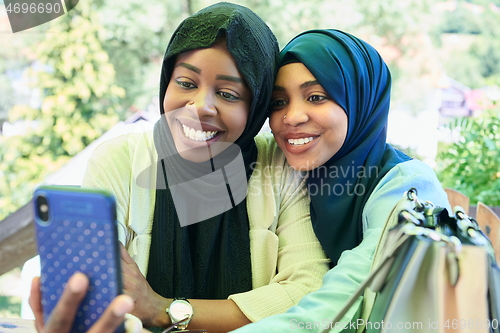 Image of african female friends using smart phone together